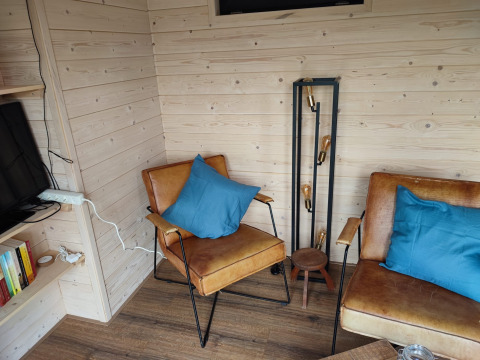 Gemütliche Glamping-Ecke bei Stadslandgoed De Heicohoeve mit Ledersesseln, blauen Kissen und Stehlampe.