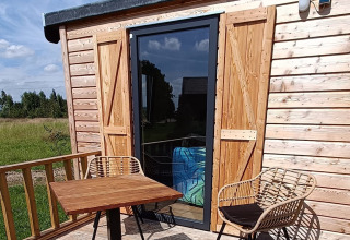 Terrazza esterna di Stadslandgoed De Heicohoeve - Pipowagens Gelderland, con tavolo e sedie in legno.