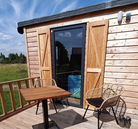 Buitenterras van Stadslandgoed De Heicohoeve - Pipowagens Gelderland met houten stoelen en tafel.