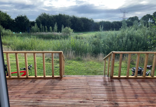 Vue depuis la terrasse en bois sur la prairie à Stadslandgoed De Heicohoeve - Pipowagens Gelderland.