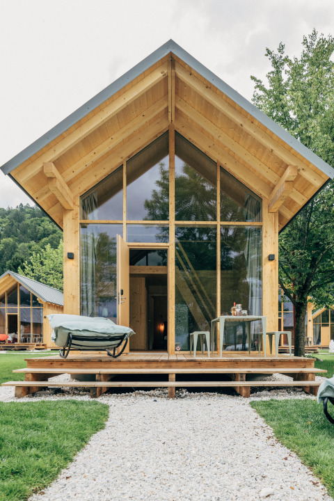 Eco lodge sul lago Millstätter See con architettura in legno moderno, grandi finestre e terrazza accogliente.