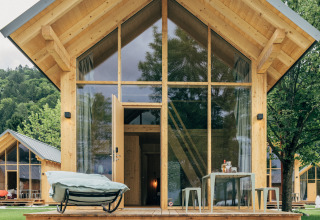 Eco lodge sul lago Millstätter See con architettura in legno moderno, grandi finestre e terrazza accogliente.