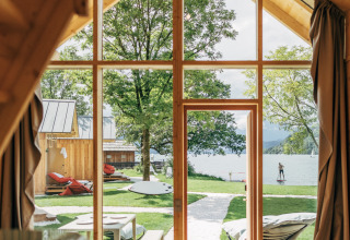 Innenansicht der Eco Lodges Millstätter See mit Blick auf Garten, See und Paddler in Österreich.