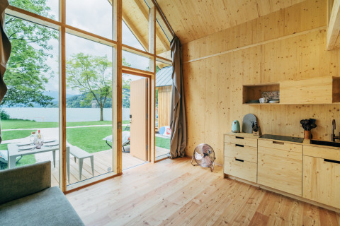 Interieur van een glamping eco lodge aan Millstätter See, Oostenrijk, licht hout en uitzicht op het meer.