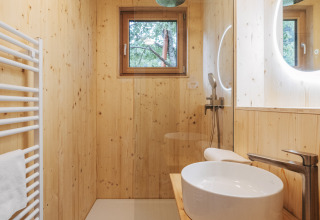 Baño moderno de madera en Eco Lodges Millstätter See - Lodges Oostenrijk con ducha y espejo redondo.