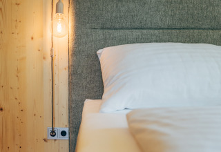 Alojamiento glamping moderno en Eco Lodges Millstätter See con pared de madera, cama y lámpara colgante.