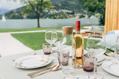 Table dressée en plein air avec vin, verres et assiettes aux Eco Lodges Millstätter See, en Autriche.