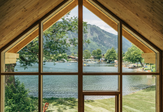 Zicht vanuit Eco Lodges Millstätter See in Oostenrijk, op het meer, bergen en het kampeerterrein.