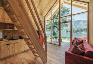 Intérieur des Eco Lodges Millstätter See en Autriche avec bois, grande baie vitrée et vue sur le lac.
