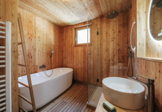 Bagno in legno con vasca, doccia e lavabo presso Eco Lodges Millstätter See, soggiorno glamping.