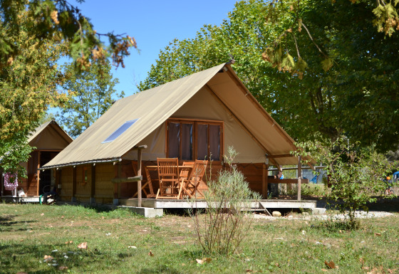 Glamping-overnatning ved Camping Détente et Clapotis omgivet af grønne træer i Auvergne-Rhône-Alpes.