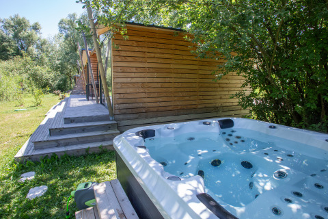 Bubbelbad buiten en moderne houten cabins in de natuur bij Camping Détente et Clapotis - Glamping Auvergne-Rhône-Alpes.