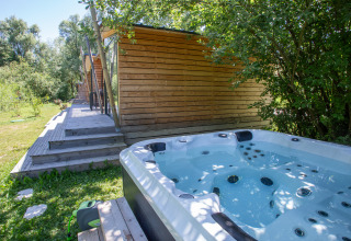 Außenwhirlpool und moderne Holzhütten im Grünen bei Camping Détente et Clapotis - Glamping Auvergne-Rhône-Alpes.