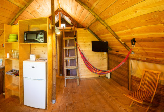 Interno di una tenda glamping presso Camping Détente et Clapotis in Auvergne-Rhône-Alpes, con cucina e soppalco.