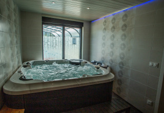 Jacuzzi intérieur à eau bouillonnante et mur carrelé au Camping Détente et Clapotis - Glamping Auvergne-Rhône-Alpes.
