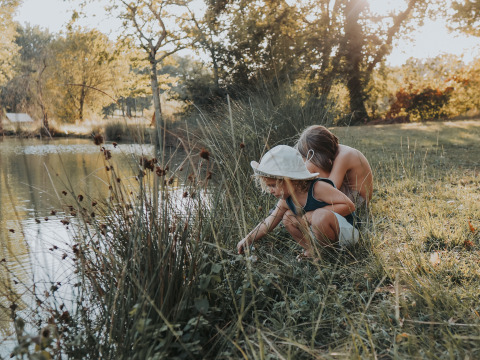 Dos niños exploran junto al lago en Whaka Lodge, glamping en la naturaleza del sur de Francia.