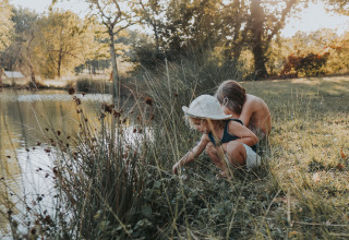 Deux enfants explorent au bord d’un lac au Whaka Lodge, camp nature glamping dans le sud de la France.