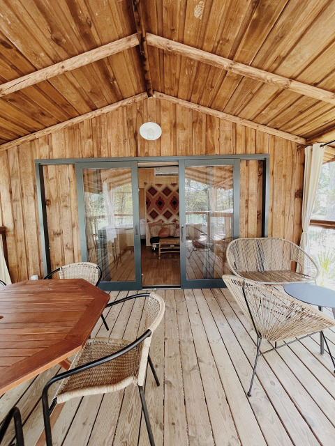 Terrazza in legno con arredi moderni al Whaka Lodge Glamping nel Sud della Francia, immersa nella natura.