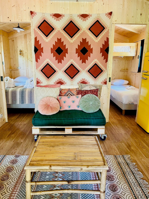 Cozy glamping accommodation at Whaka Lodge in South France with rustic decor and vibrant cushions.