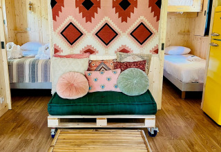 Cozy glamping accommodation at Whaka Lodge in South France with rustic decor and vibrant cushions.