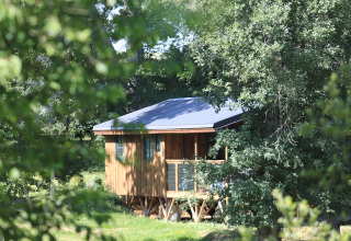 Wooden glamping cabin at Whaka Lodge - Lifestyle nature camp in South France, nestled among green trees.