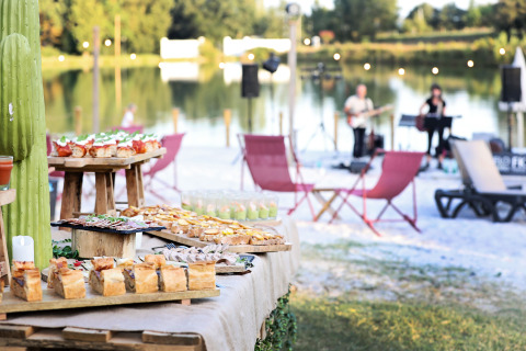 Outdoor buffet with delicious food and live music by the lake at Whaka Lodge glamping in South France.