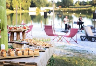 Udendørs buffet med lækker mad og musikoptræden ved søen på Whaka Lodge glamping i Sydfrankrig.