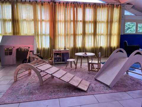 Area giochi interna al glamping Whaka Lodge con giocattoli in legno, scivolo e mobili per bambini.