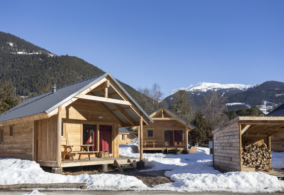 Glamping accommodatie bij Huttopia Winter Chalets – Bourg St Maurice met houten huisjes in besneeuwde bergen.