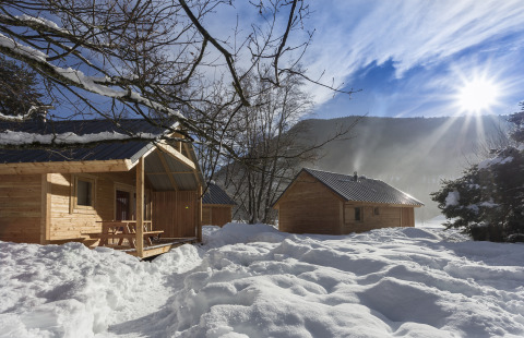 Sfeervolle houten chalets in de sneeuw bij Huttopia Winter Chalets – Bourg St Maurice, Glamping Savoie.