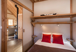 Innenansicht der Huttopia Winter Chalets – Bourg St Maurice mit gemütlichem Schlafzimmer und Küche.