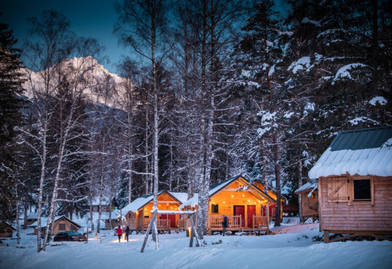 Winter-Glamping in Chalet-Hütten bei Huttopia Vanoise, Bozel, Savoie, umgeben von verschneiten Bäumen.
