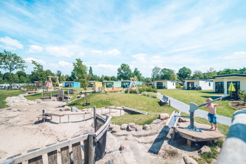 Kinderen spelen op een avontuurlijke speeltuin bij vakantiepark Ackersate in Gelderland, Nederland, met chalets.