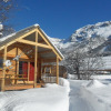 Snow-covered wooden chalet at Huttopia Winter Chalets – Vallouise, with mountains in the French Alps.