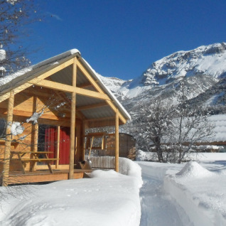 Met sneeuw bedekte houten chalet bij Huttopia Winter Chalets – Vallouise, zicht op de Franse Alpen.
