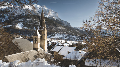 Vista invernale su Vallouise con tetti innevati e montagne vicino a Huttopia Winter Chalets, Alpi francesi.