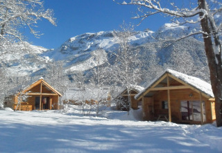 Met sneeuw bedekte houten chalets bij Huttopia Winter Chalets – Vallouise, glamping in de Franse Alpen.
