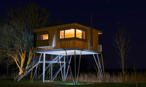 Glamping boomhut accommodatie bij Elbinselhof Krautstrand, verlicht in de nacht onder een sterrenhemel.
