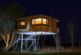 Træhytte glamping indkvartering på Elbinselhof Krautstrand, oplyst om natten under stjernehimmel.