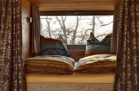 Lit de glamping douillet avec une literie colorée dans les Boomhutten d’Elbinselhof Krautstrand.