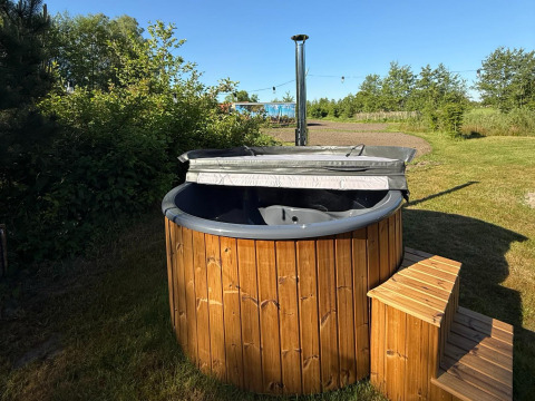 Buiten hottub van hout met opstapje bij Koakelbonts Lovenest - Safaritent Gelderland in het grasveld.