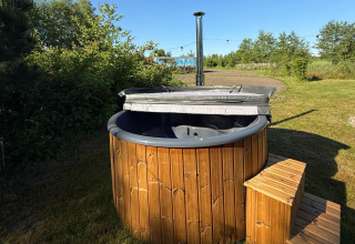 Holz-Whirlpool mit Stufen auf grüner Wiese im Freien bei Koakelbonts Lovenest - Safaritent Gelderland.