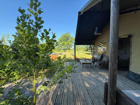 View from the wooden deck at Koakelbonts Lovenest - Safaritent Gelderland with seating and greenery.