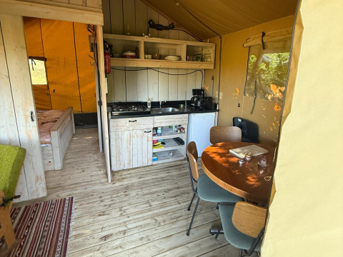 Binnenaanzicht van Koakelbonts Lovenest - Safaritent Gelderland met keuken, eethoek en slaapruimte.