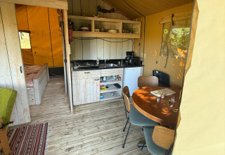 Interior view of Koakelbonts Lovenest - Safaritent Gelderland, showing kitchen, dining, and bedroom.