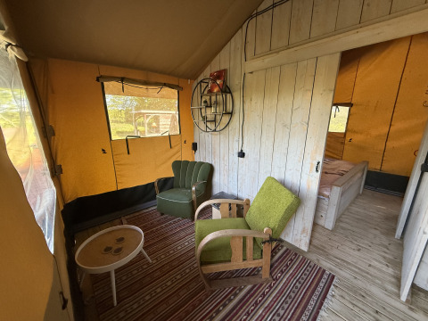 Interieur van Koakelbonts Lovenest - Safaritent Gelderland, knusse zithoek met groene stoelen.