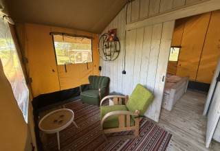 Interior de Koakelbonts Lovenest - Safaritent Gelderland, área de descanso acogedora con sillas verdes.