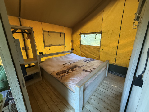 Intérieur du Koakelbonts Lovenest - Safaritent Gelderland glamping avec lit et sol en bois.