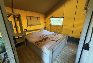 Indvendigt billede af Koakelbonts Lovenest - Safaritent Gelderland glamping med seng og trægulv.