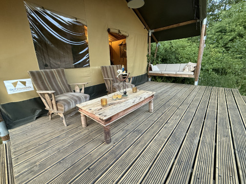Buitenveranda met comfortabele stoelen en tafel bij Koakelbonts Lovenest - Safaritent Gelderland.